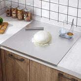 Kneaded dough on a kitchen counter with kitchen utensils and ingredients in the background.