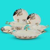 Ceramic dish set with floral patterns and gold accents on a turquoise background
