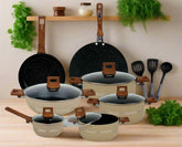 Set of cookware with speckled black interior and wooden handles on a white background