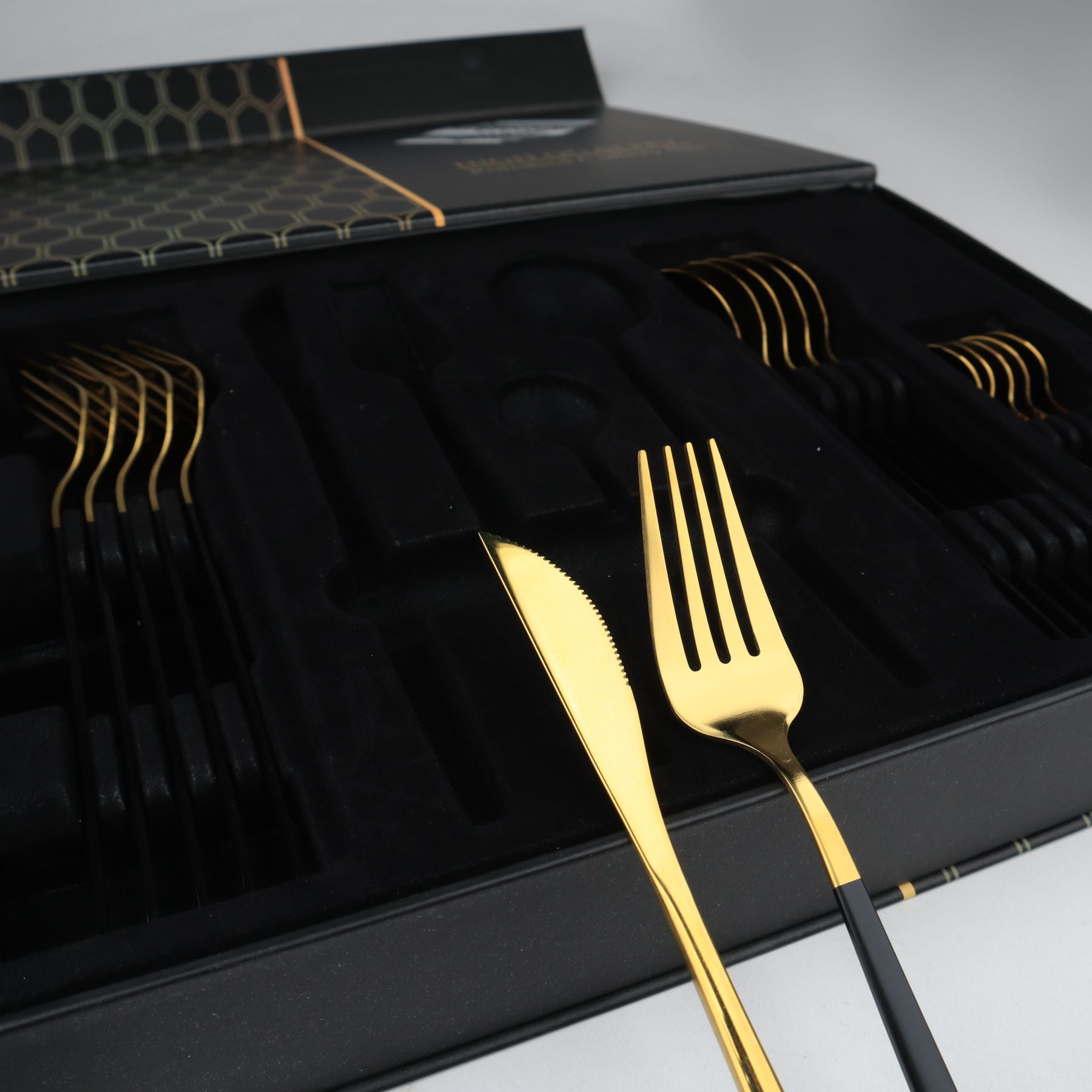 Gold cutlery set with black handles in a black box by majestic chef cookware