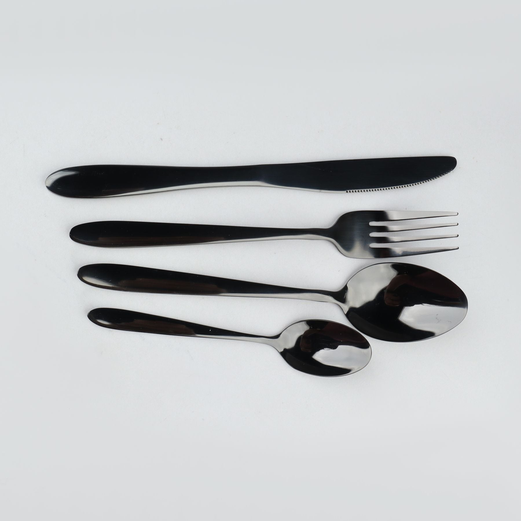 Set of stainless steel pvd coated cutlery including a knife, fork, and two spoons on a light gray background.