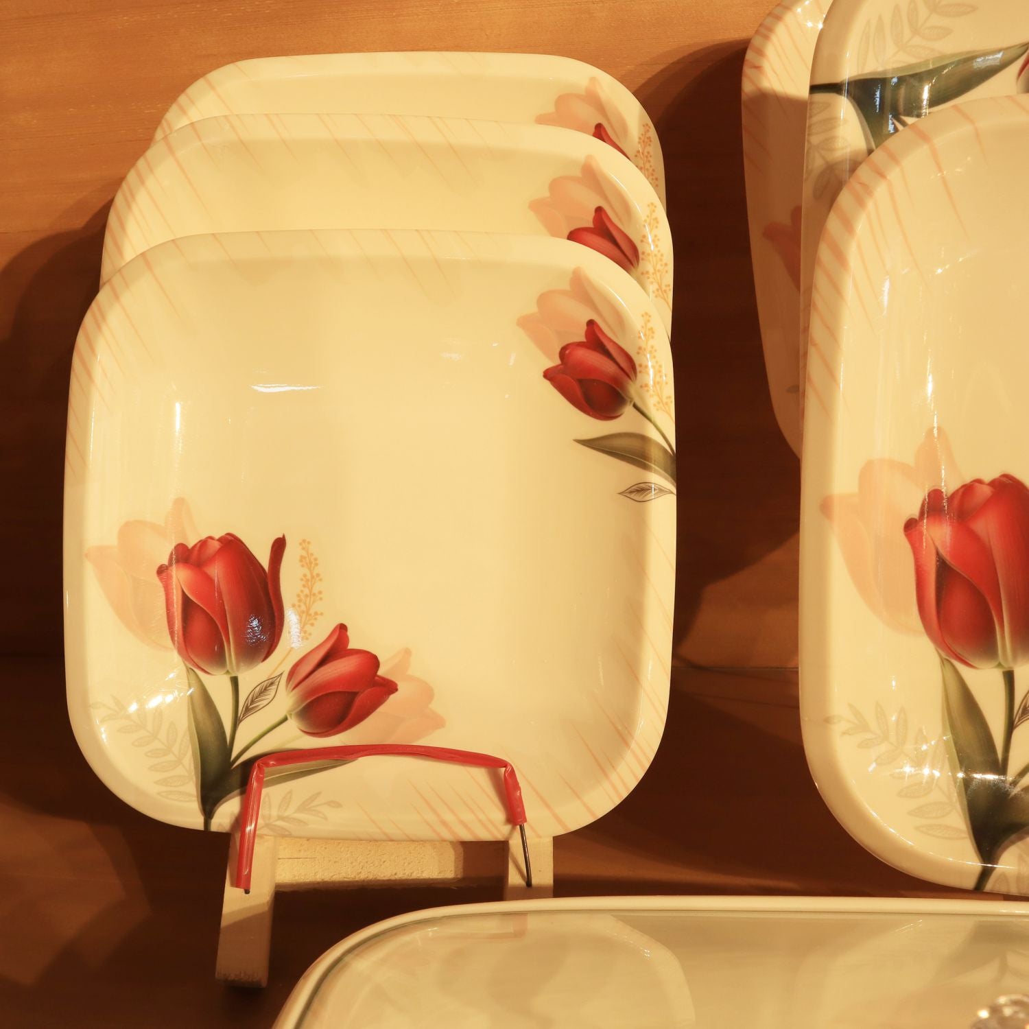 Set of ceramic dishes with red tulip design on a wooden surface