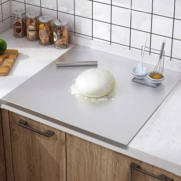 Kneaded dough on a kitchen counter with kitchen utensils and ingredients in the background.