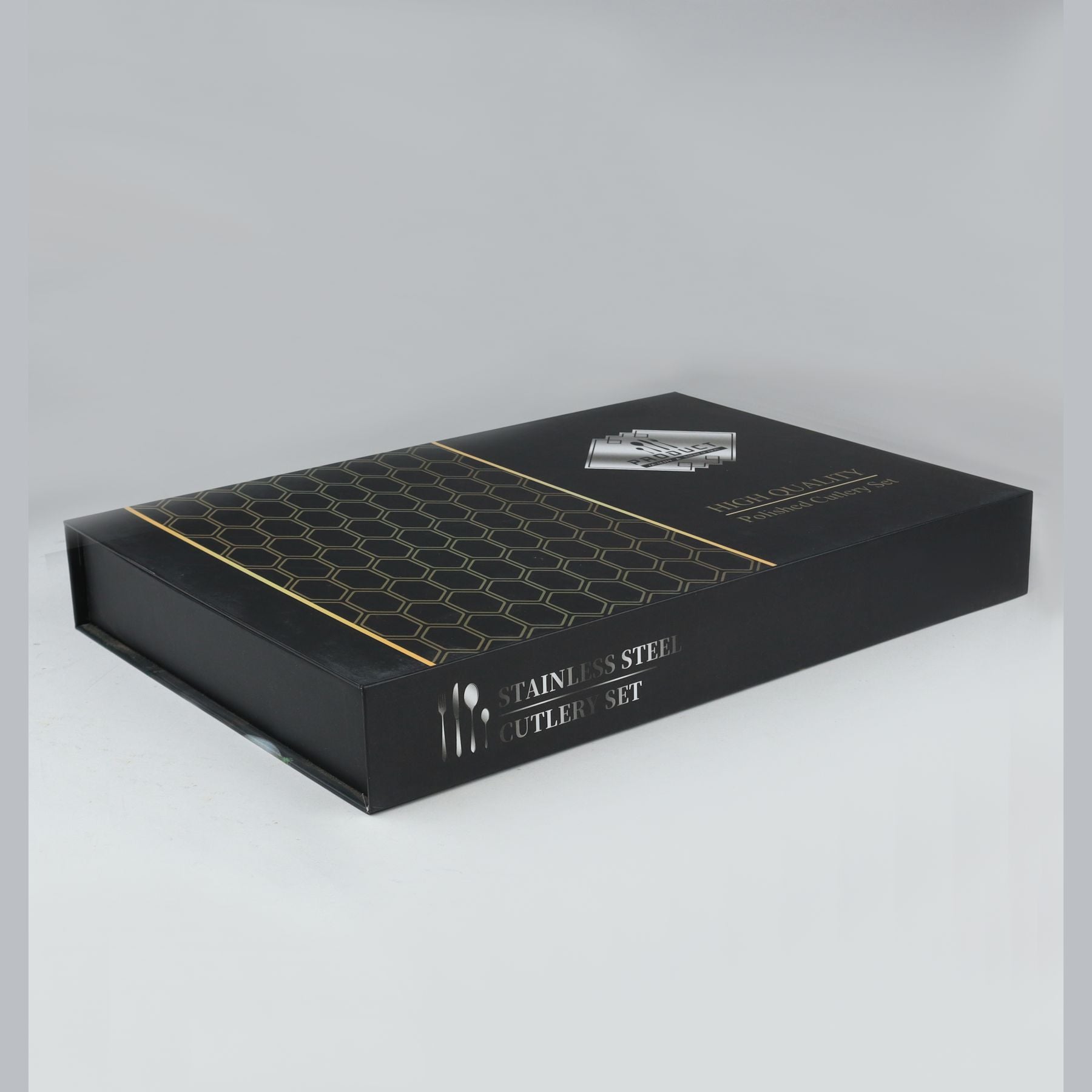 Black box with gold accents containing a stainless steel cutlery set on a gray background